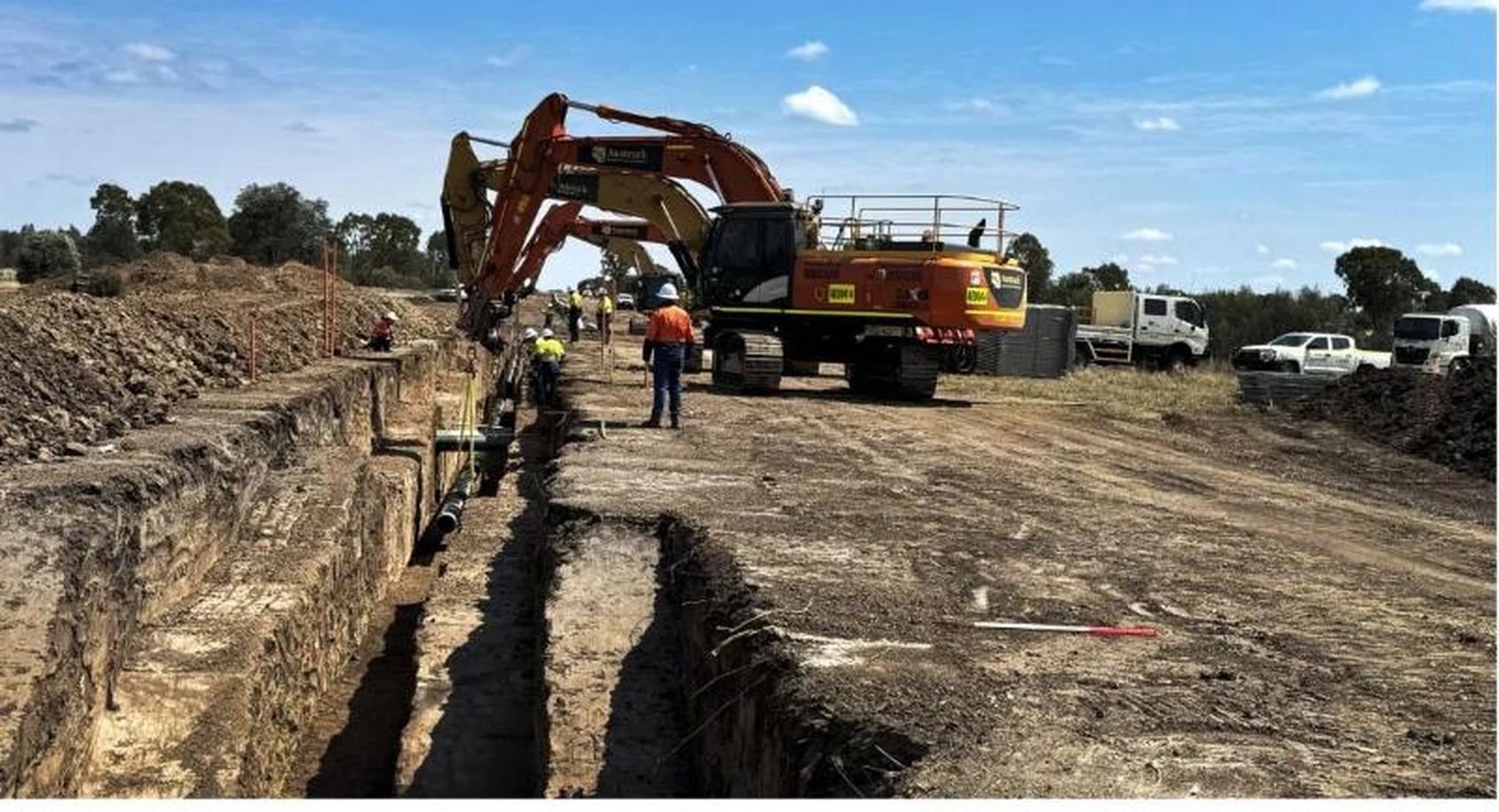 Excavator working alongside a pipeline trench